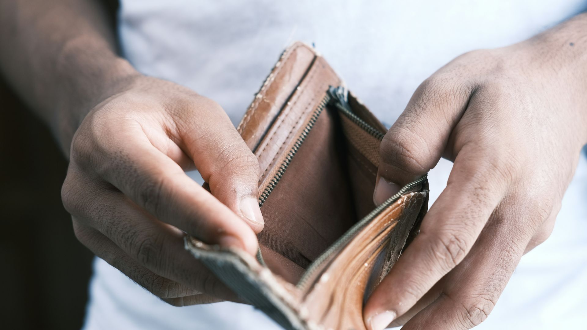 person holding brown leather bifold wallet