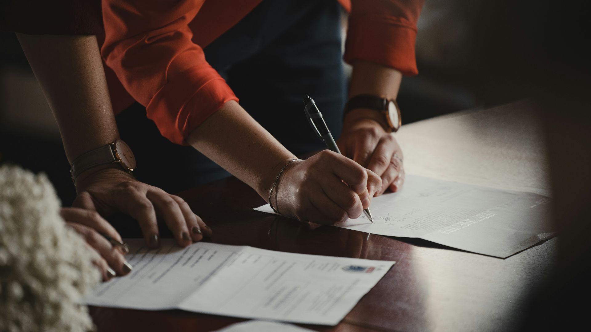 person in orange long sleeve shirt writing on white paper