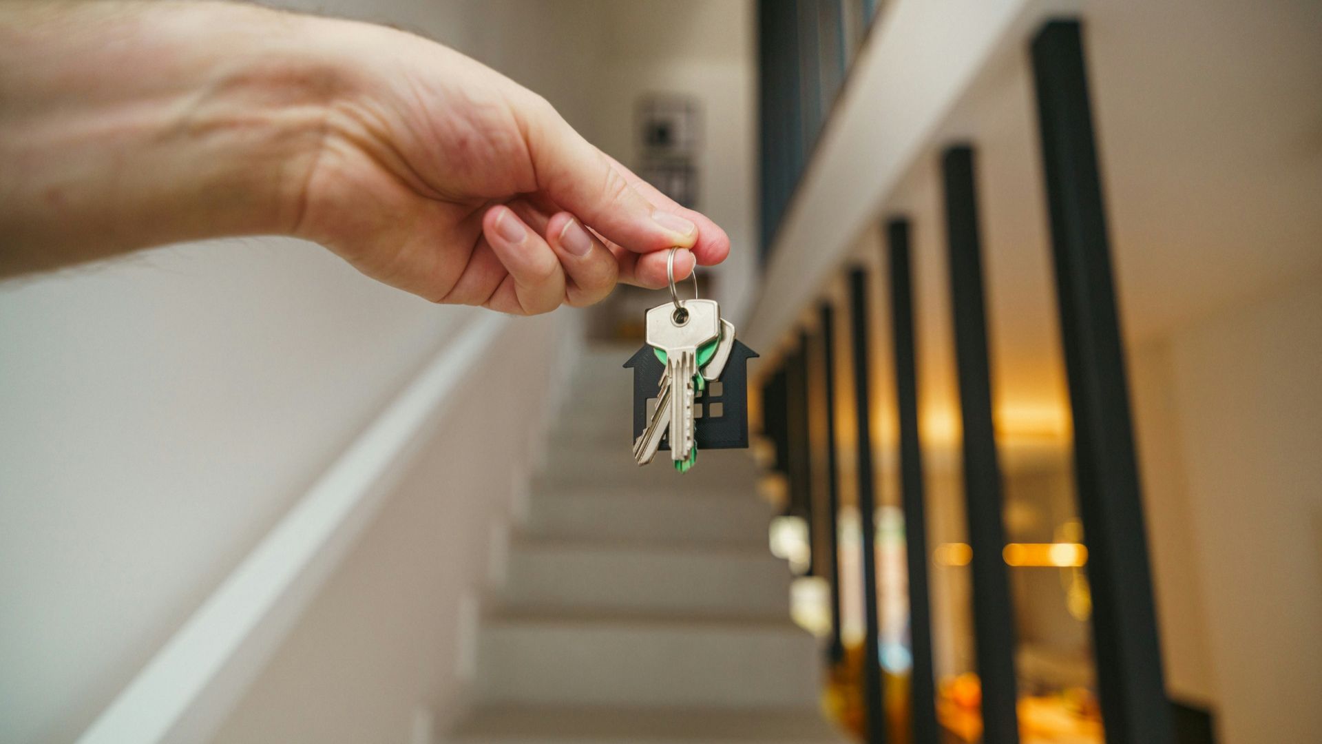 Here's a possible caption: keys being held in front of a staircase.