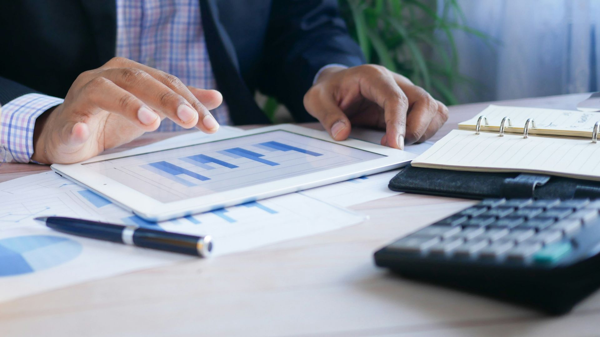 person in black suit jacket holding white tablet computer