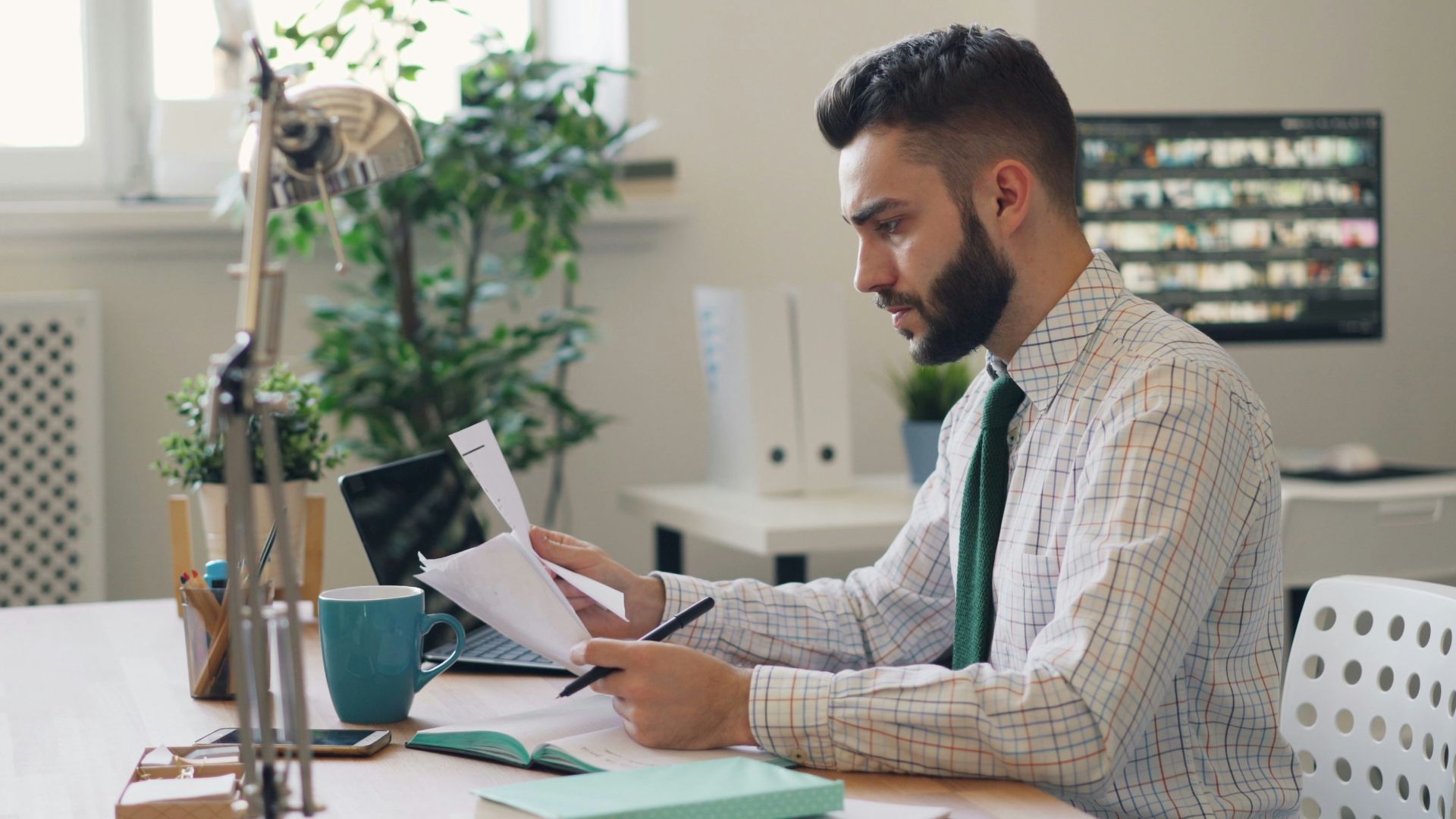 a man sitting at a desk with a laptop and papers