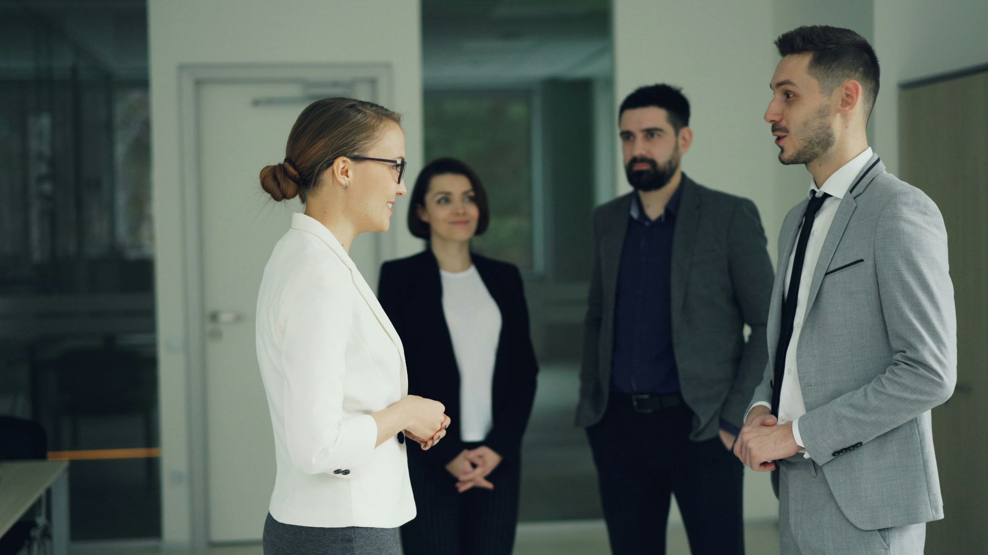 Business professionals conversing in a modern office hallway.