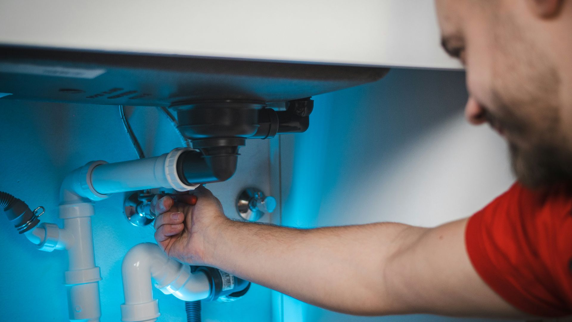 a man working on a pipe in a wall