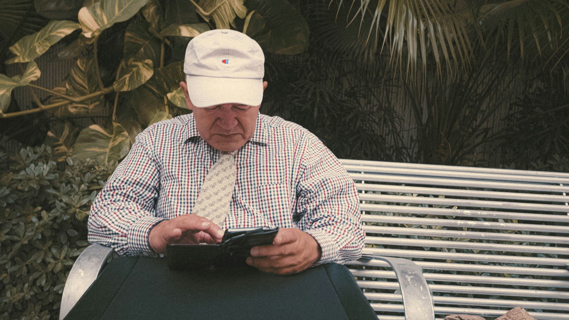a man sitting on a bench looking at his cell phone