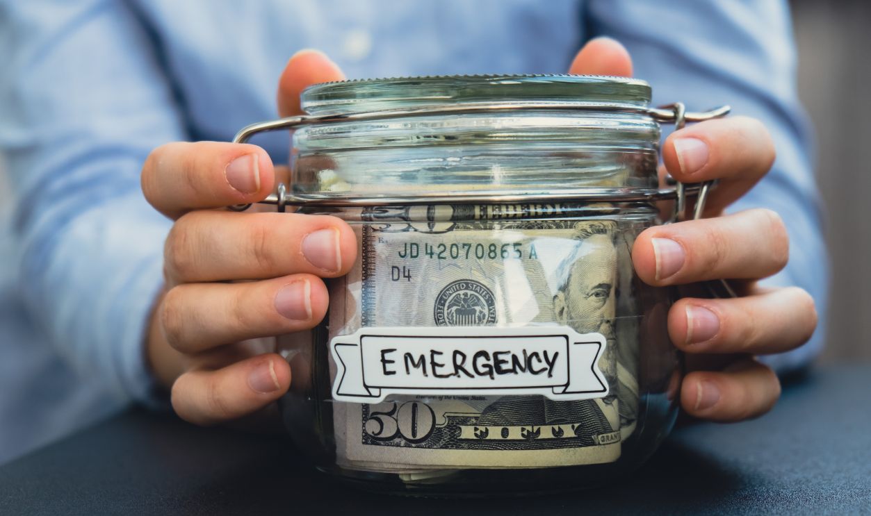 Female hands Saving Money In Glass Jar filled with Dollars banknotes.