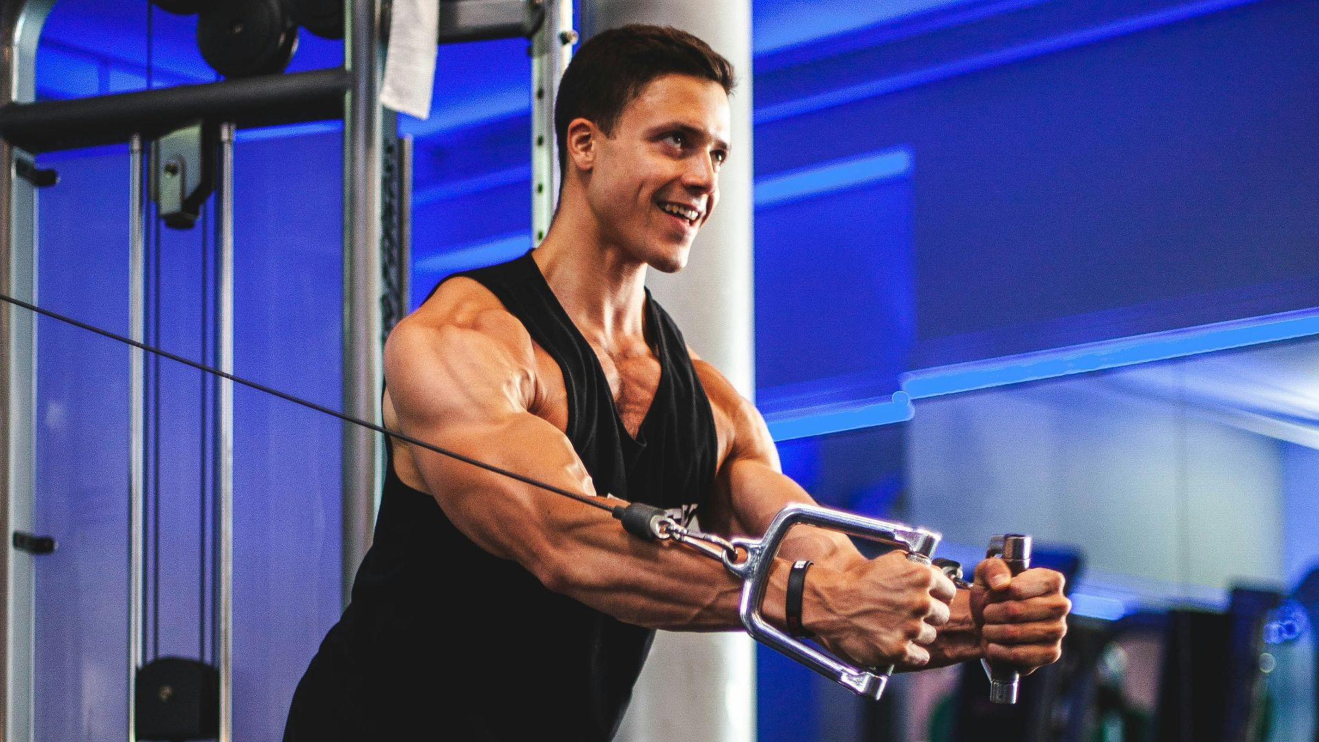 man in black tank top and gray shorts holding black smartphone