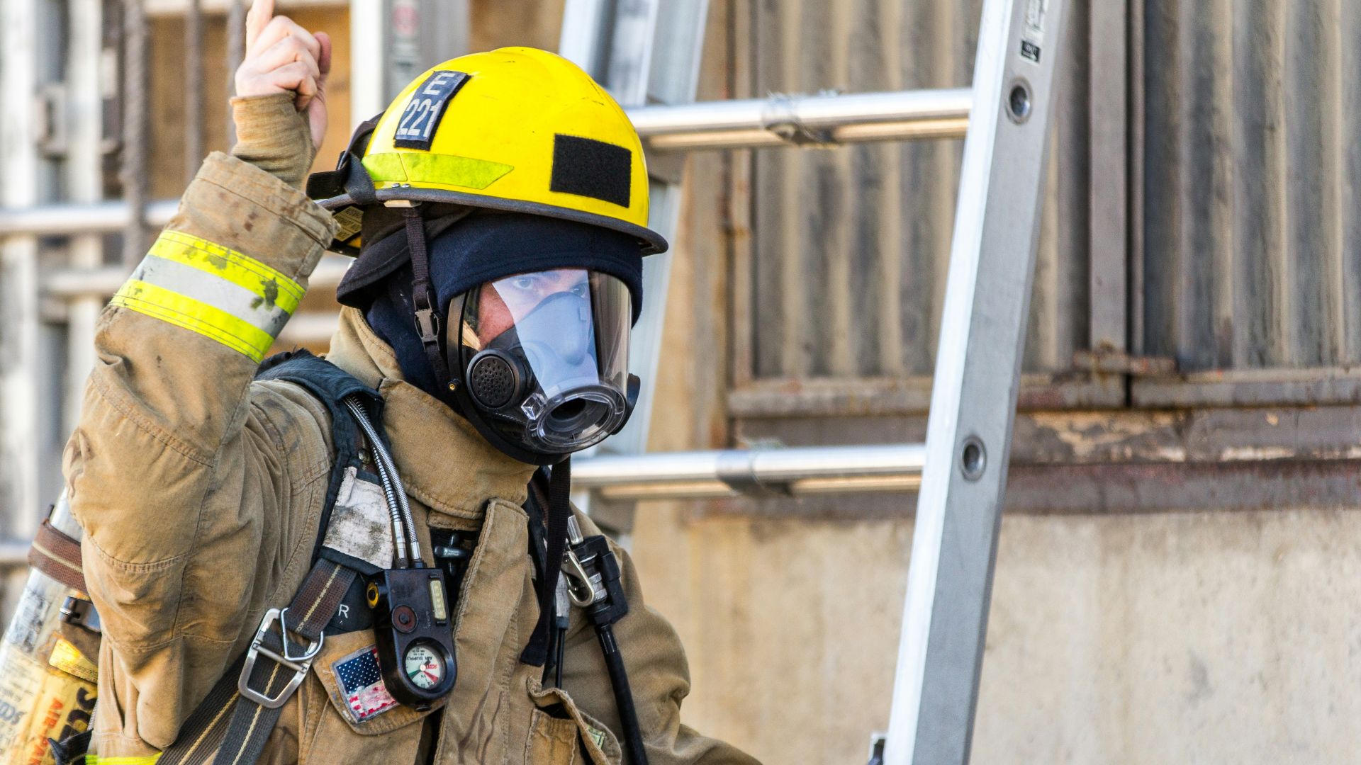 fireman wearing mask standing and about to climb on ladder