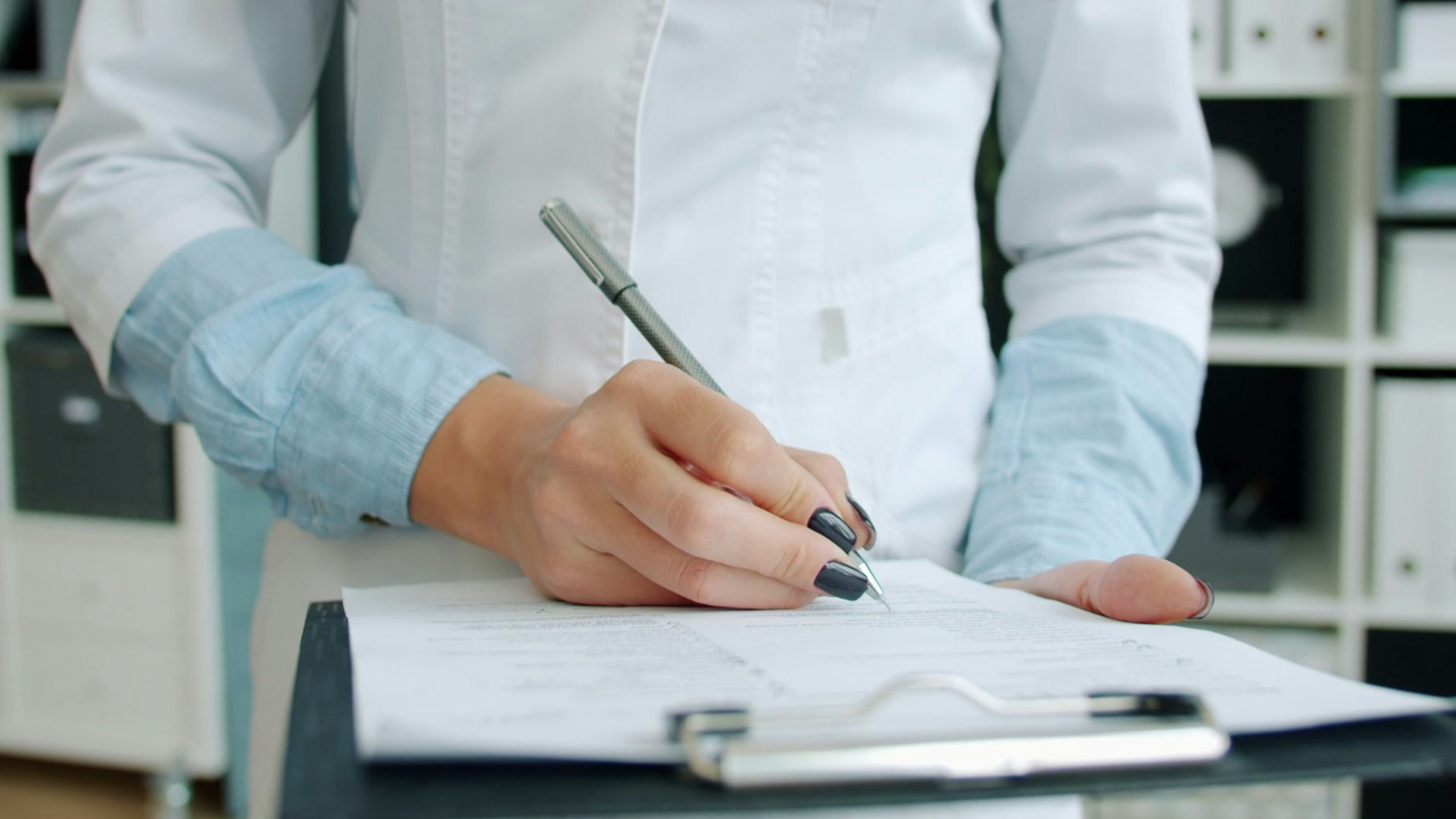 Doctor writing on clipboard in office