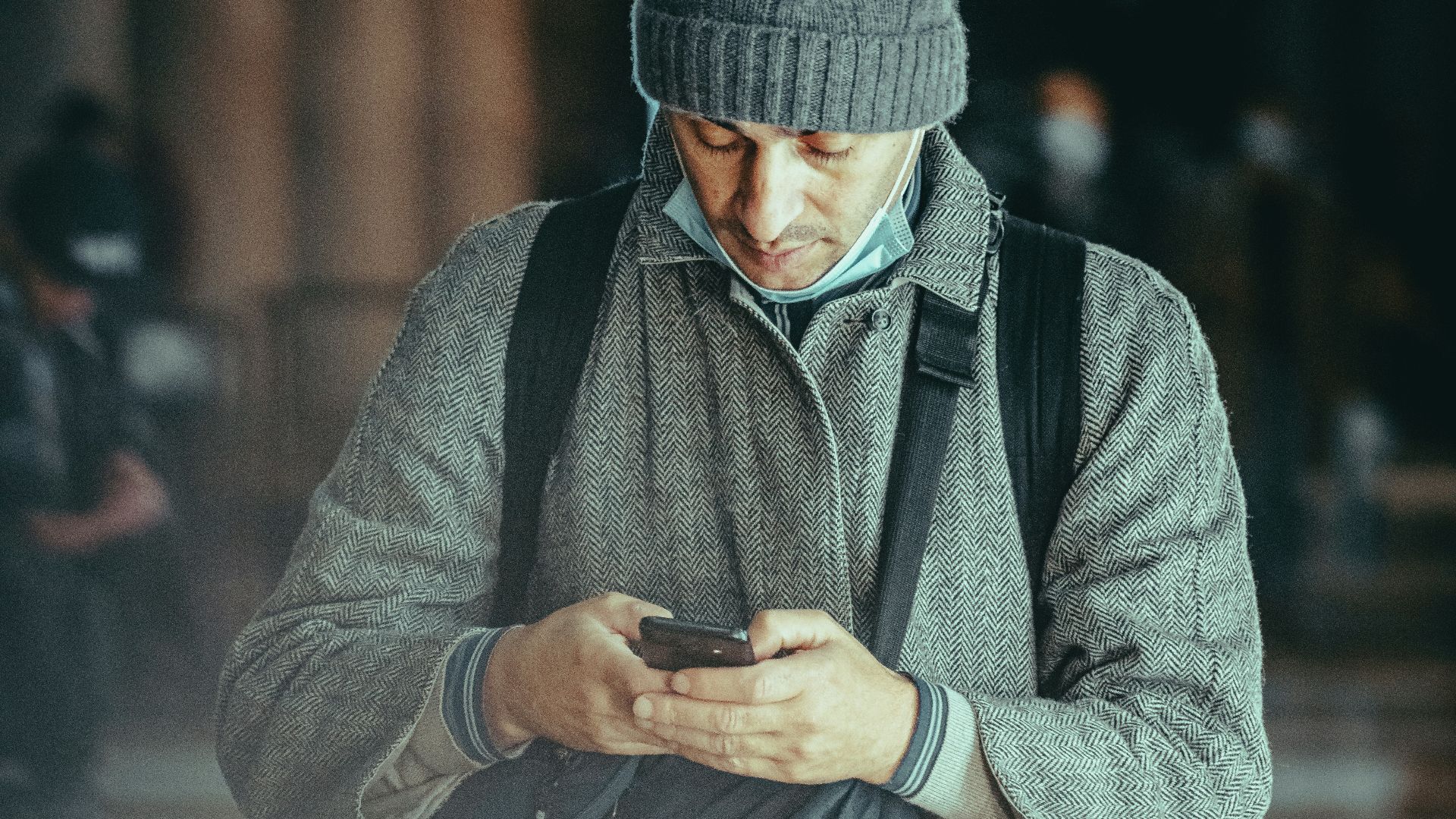 man in gray knit cap and black jacket holding black rifle