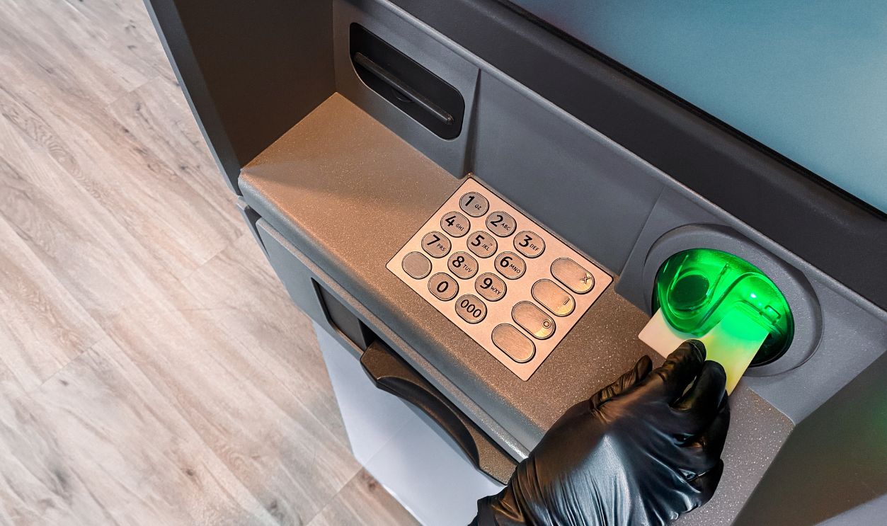 Thief hand with black glove stealing money. Burglar committing robbery. Financial crime. Hacking ATM machine. Breaking system. Withdrawing cash using stolen debit card. Stealing cash from bank account