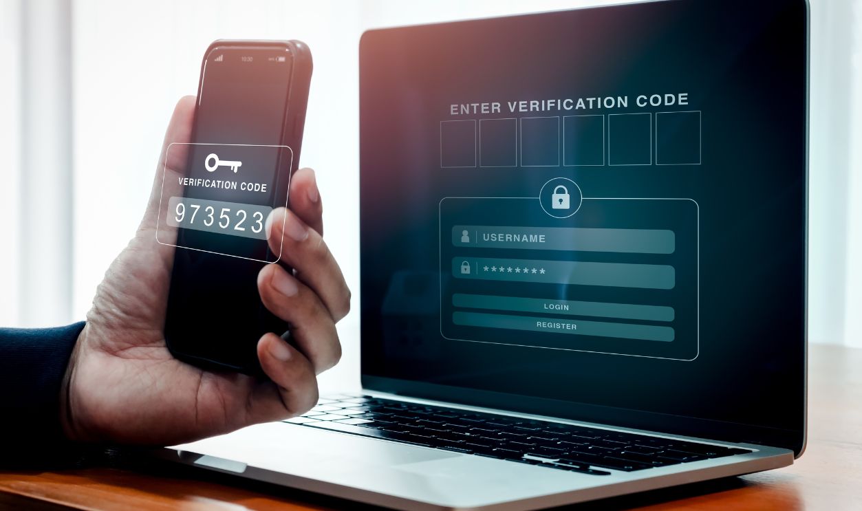 Multi factor authentication, 2fa cyber security concept. Passcode key on smartphone in person's hand while empty password box for enter verification code showing on laptop screen for sign in website.