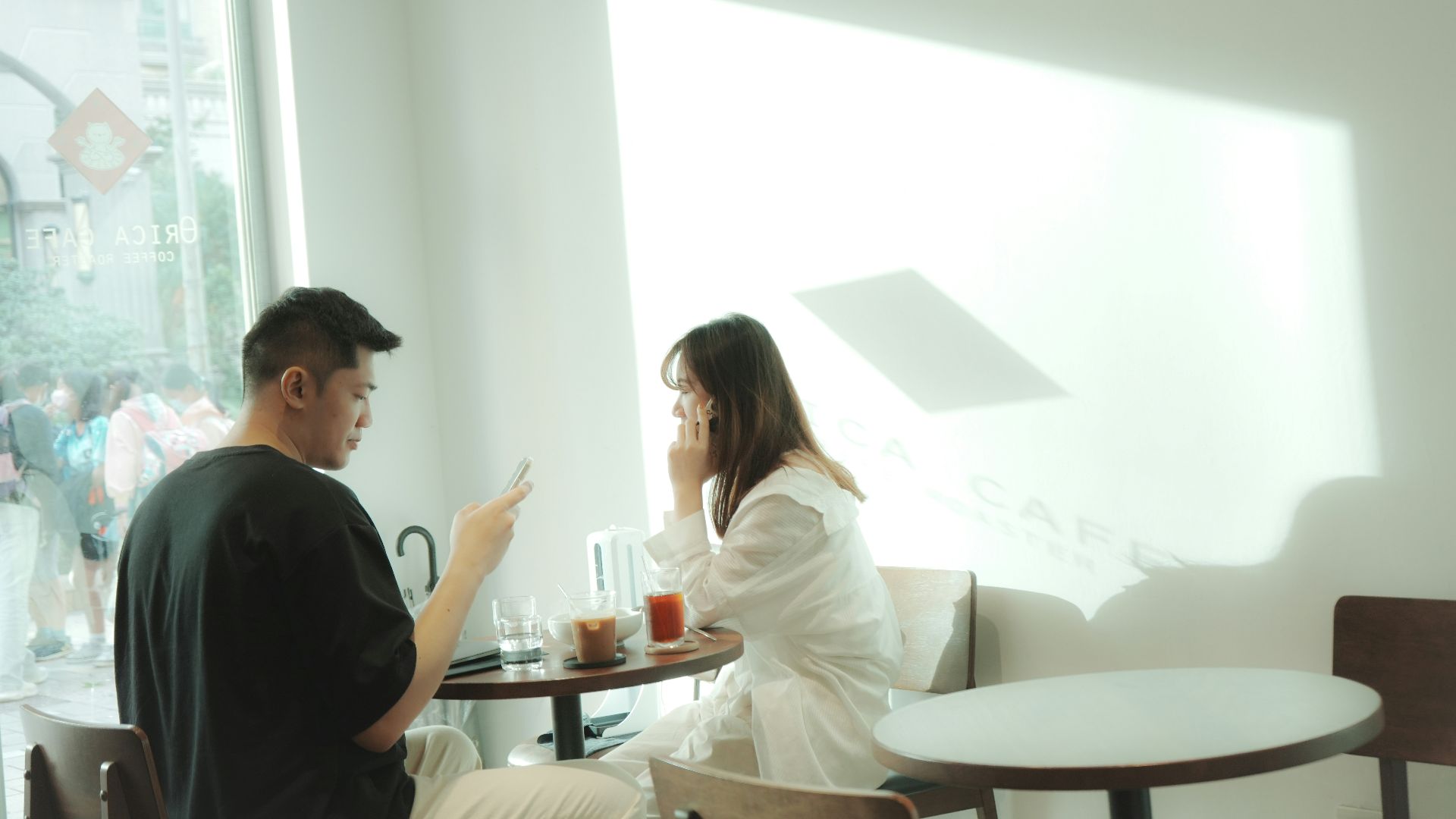 a man and woman sitting at a table in a room with a window