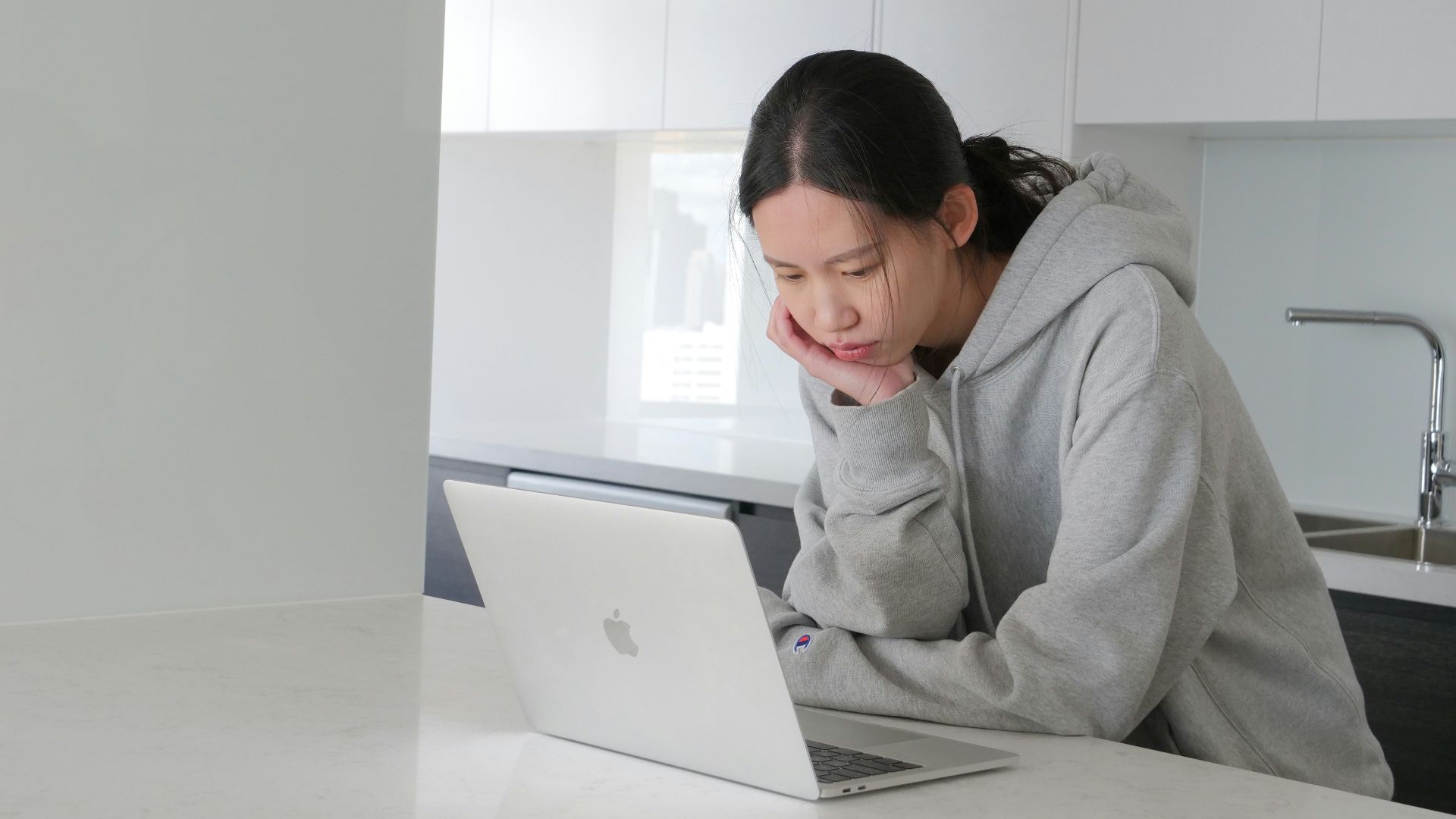 man in gray hoodie sitting beside white table