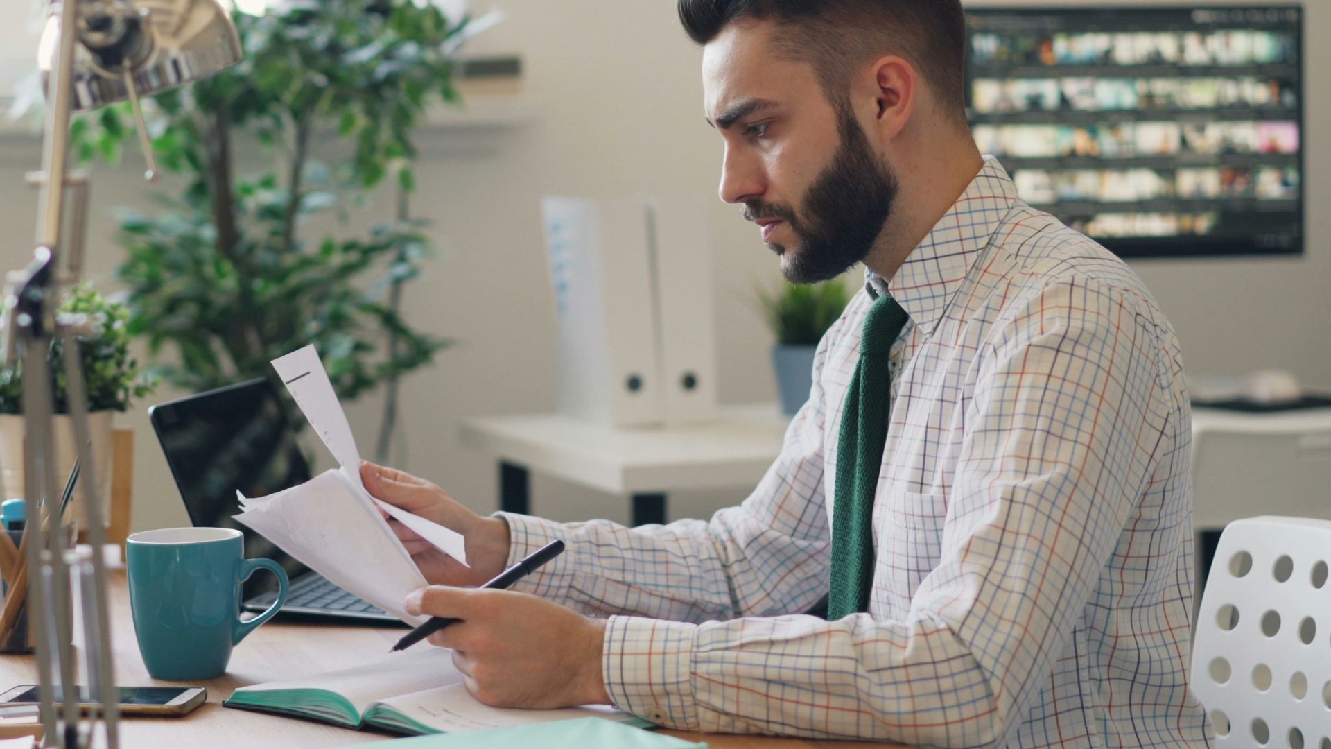 a man sitting at a desk with a laptop and papers