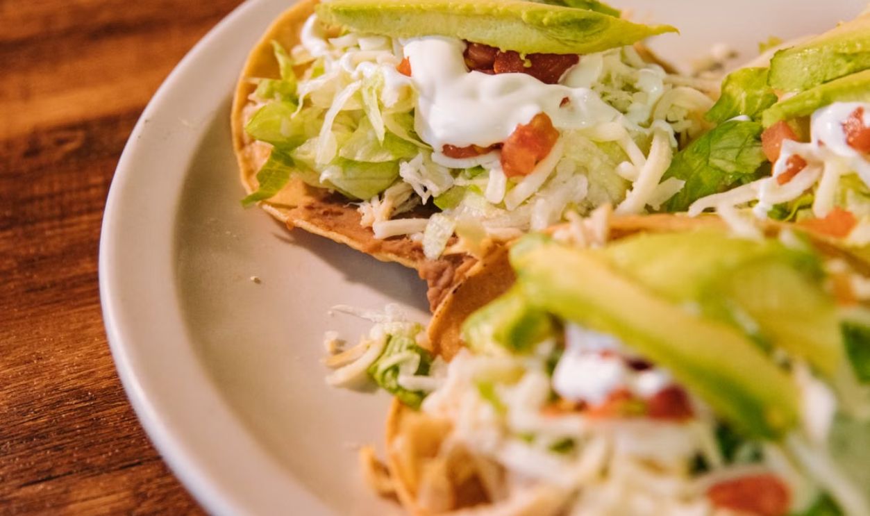 Mouth-watering close-up of Mexican tacos with avocado, cheese, and vegetables on a plate