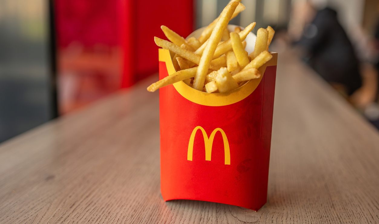 Kyiv, Ukraine - January 31 2024: Close-up of a McDonald's french fries serving, in its classic red packaging, situated on a wooden table in a Kyiv outlet.