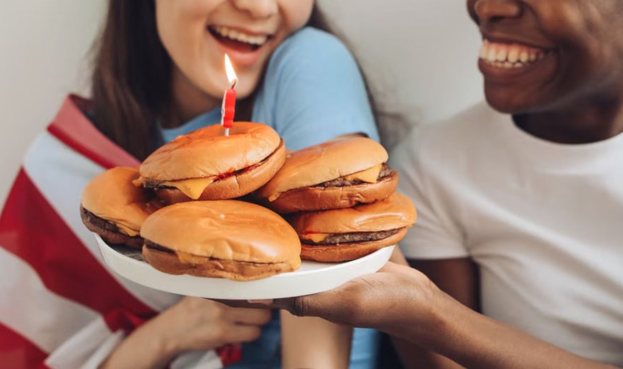 Two friends joyfully celebrating with burgers, laughter, and an American flag