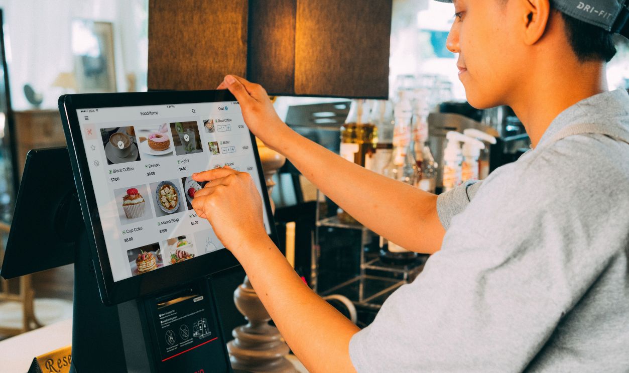 A cafe worker navigating a modern touchscreen system to manage orders