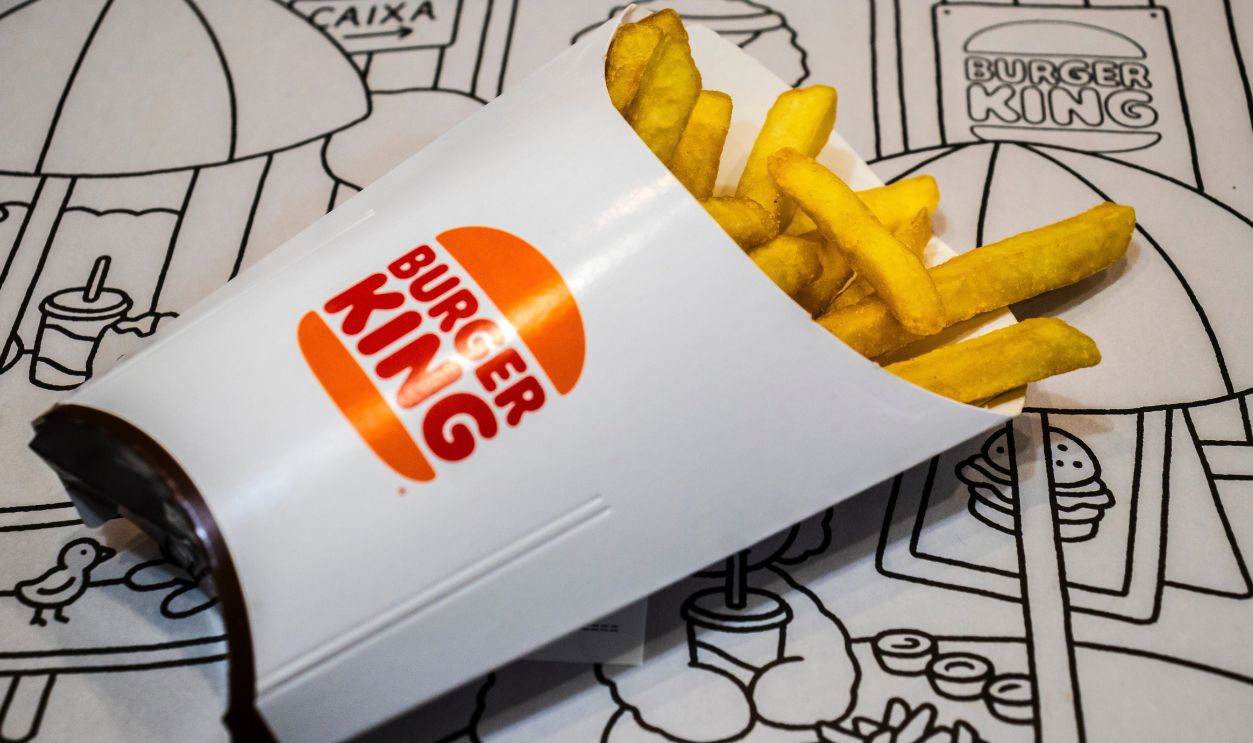 Marilia, SP, Brazil, May 29, 2025. Burger King french fries spilled from white paper bag on illustrated placemat background, showcasing fast food branding and contemporary dining culture