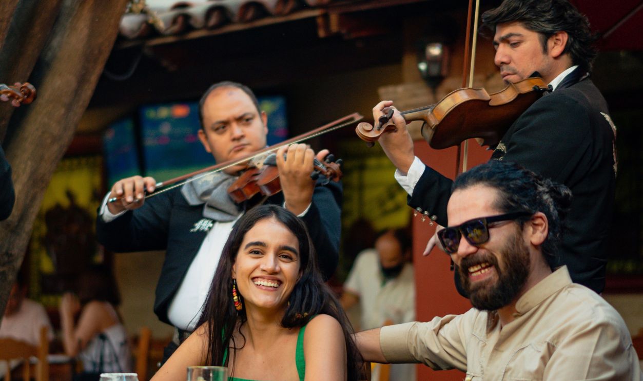 A lively outdoor scene with a mariachi band playing for a group of friends