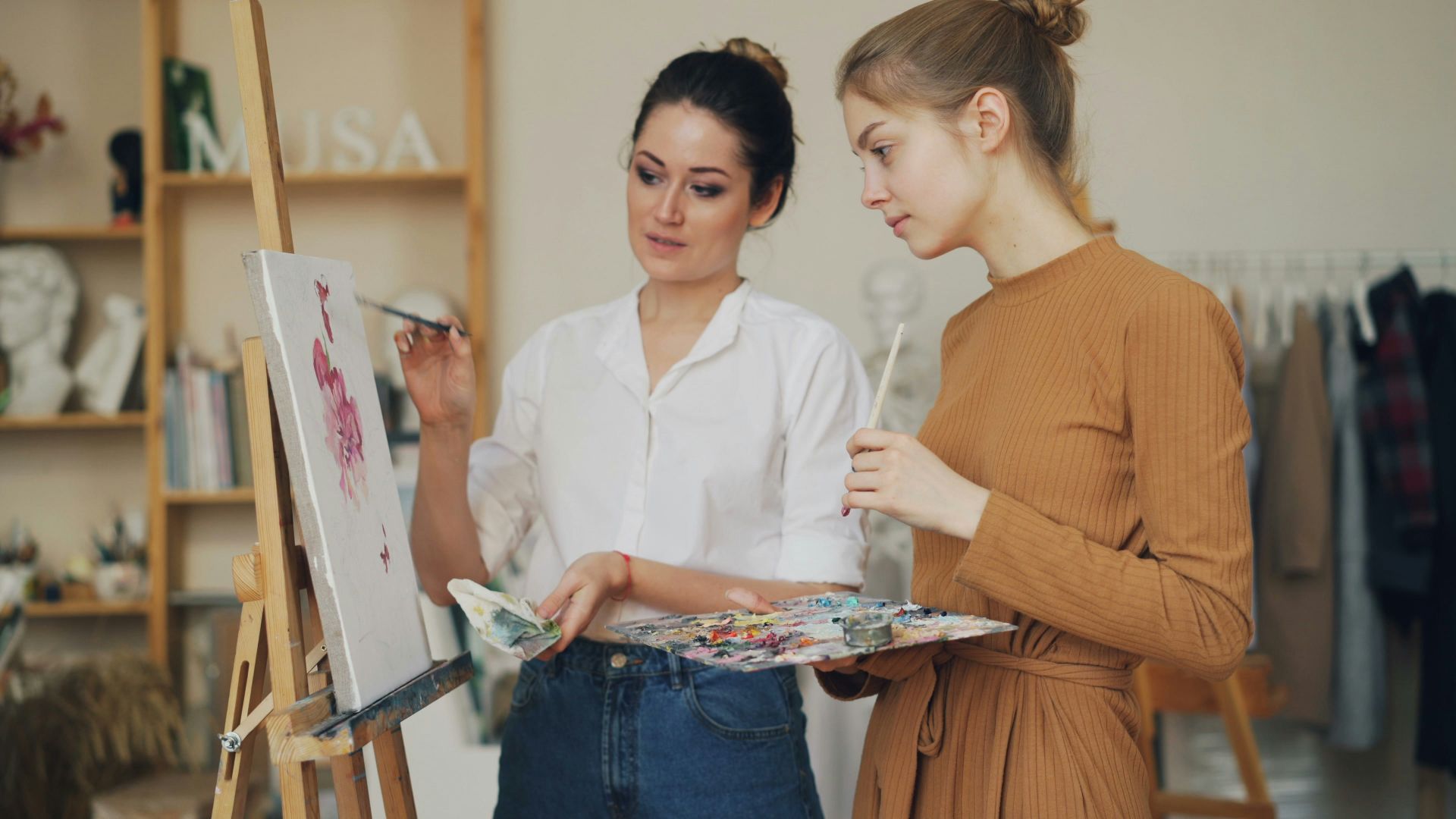 Two women are painting and discussing art