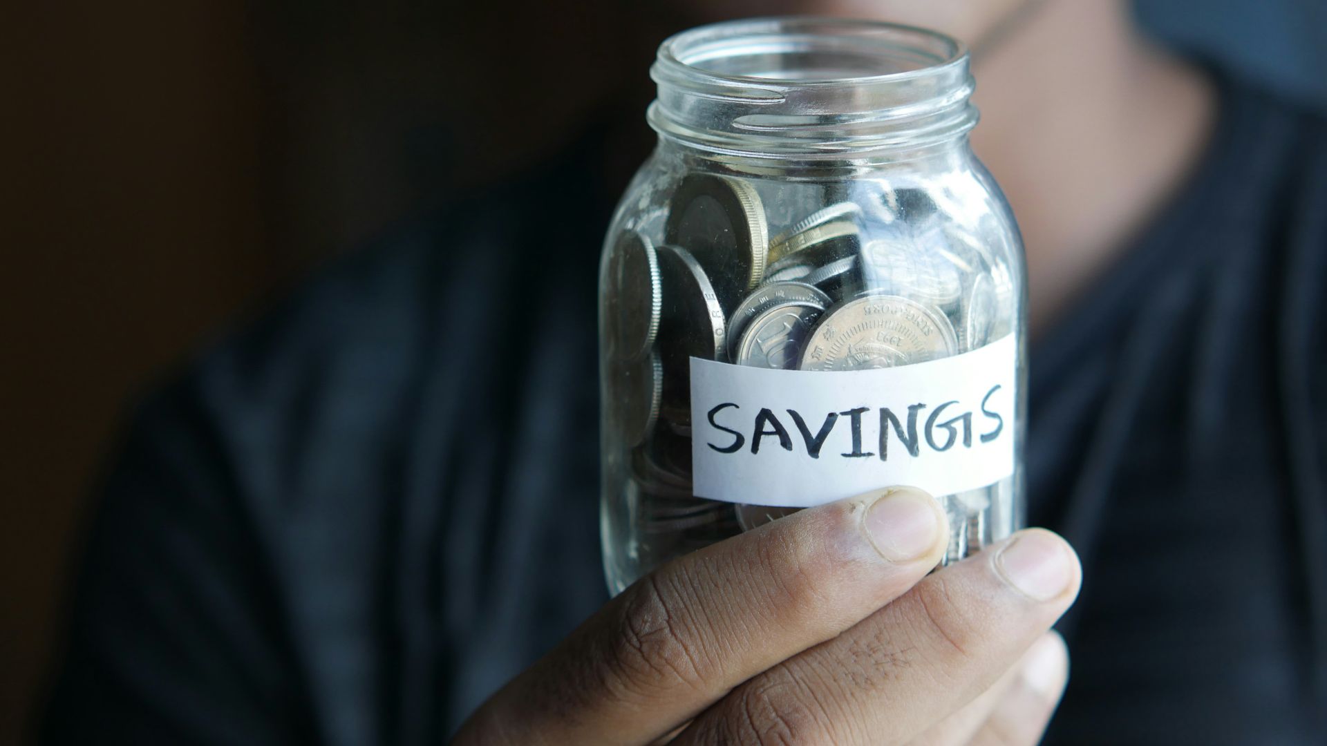 a man holding a jar with a savings label on it