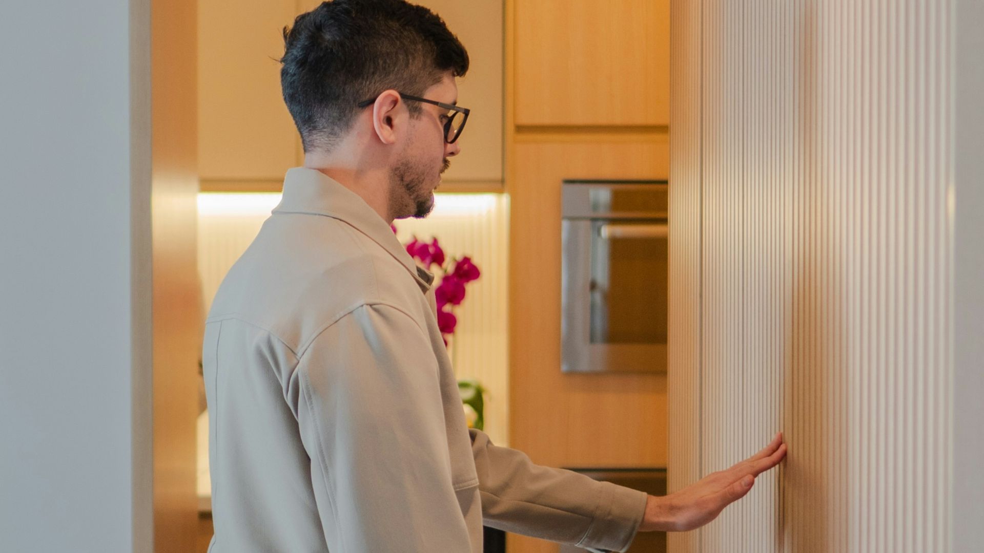 Man touching a wooden wall, modern kitchen in background