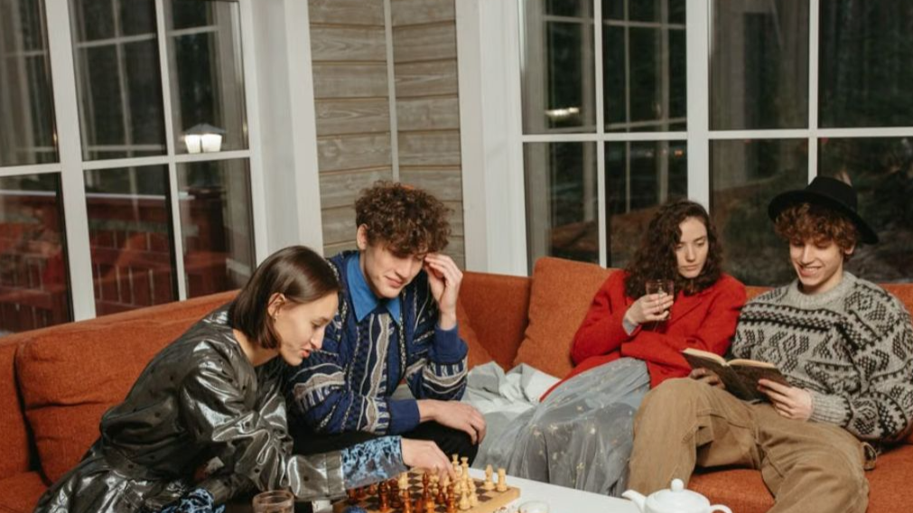 A group of friends enjoying a cozy indoor evening, sipping drinks and playing chess together.