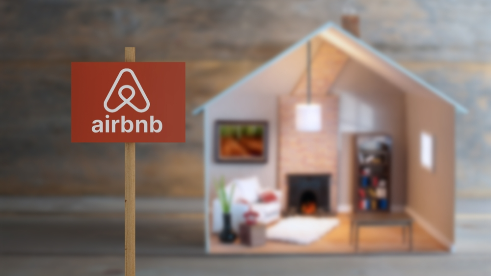 Airbnb sign next to a model house with lights on inside