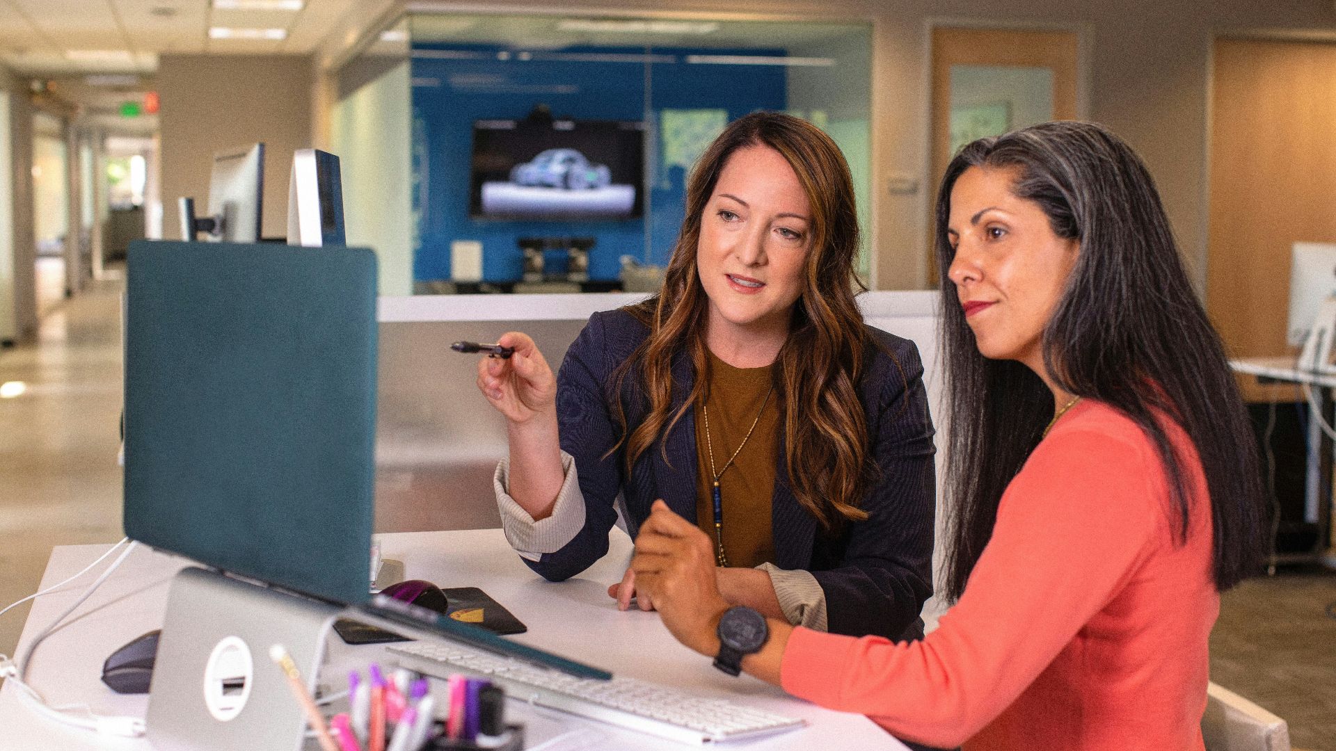 two women sitting at a table looking at a computer screen