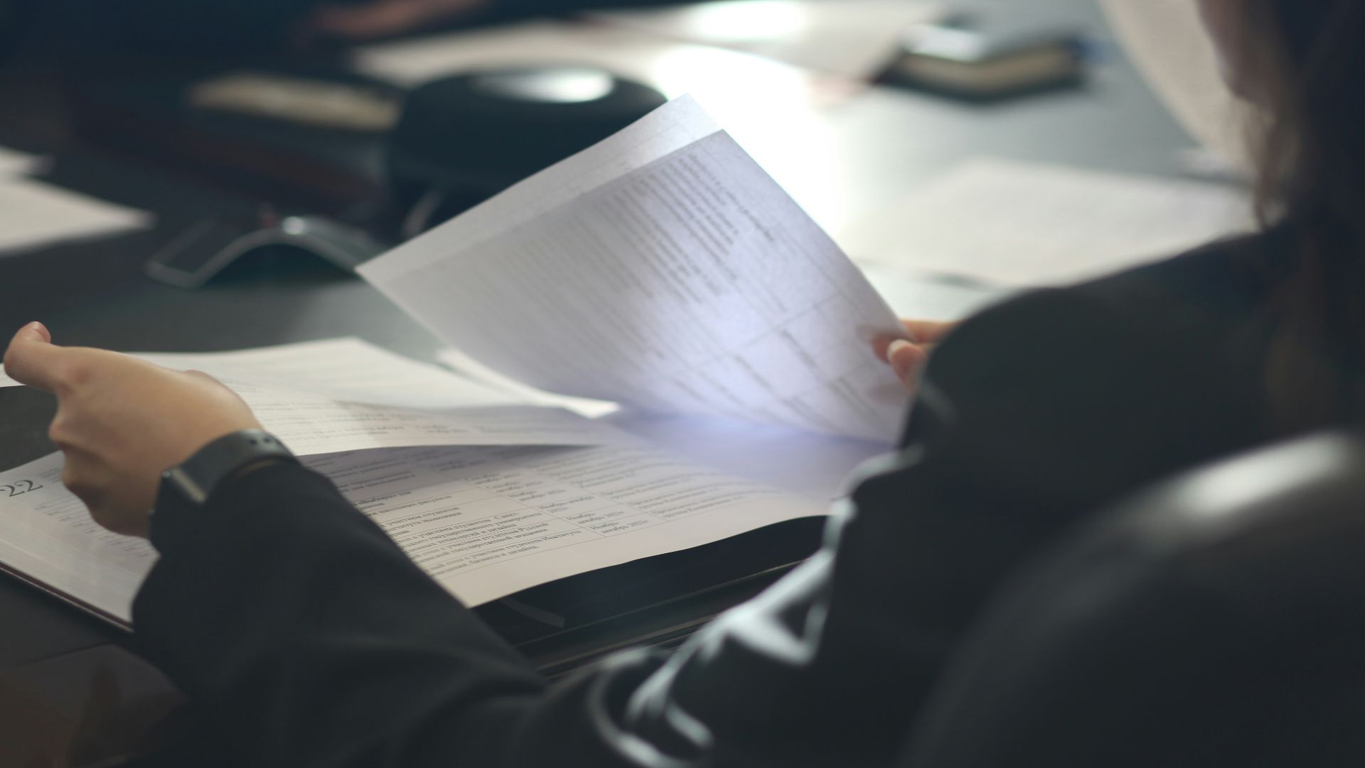 a woman sitting at a table reading a paper
