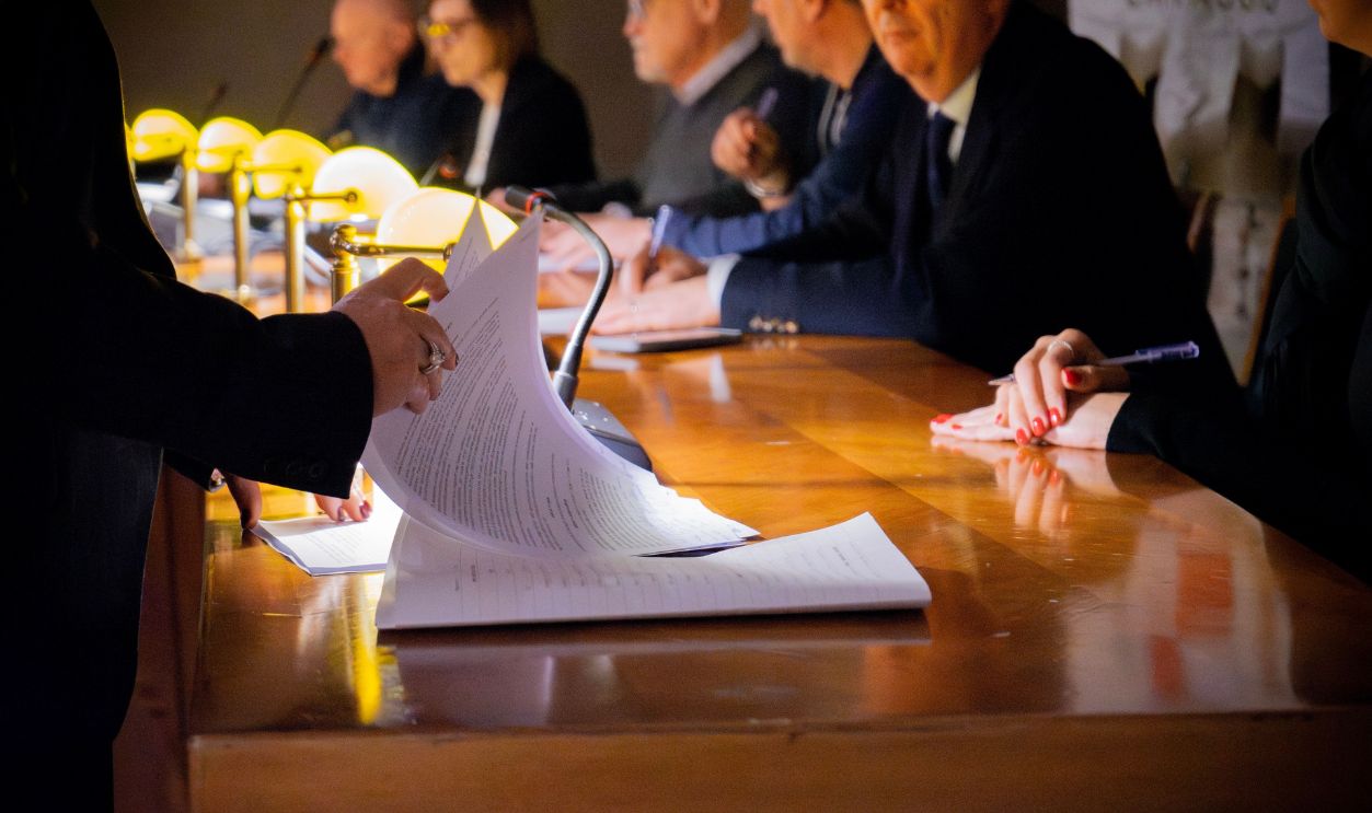 Close-up of a business meeting table with documents being reviewed and signed in Bergamo, Italy.