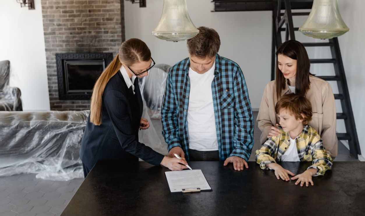 Happy family signing a real estate contract with agent inside their new home.