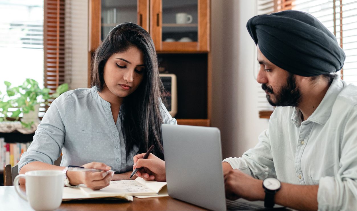Two young professionals working together at home with a laptop.