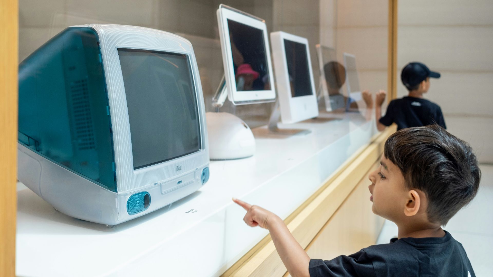 Young boy points at vintage teal imac computer display