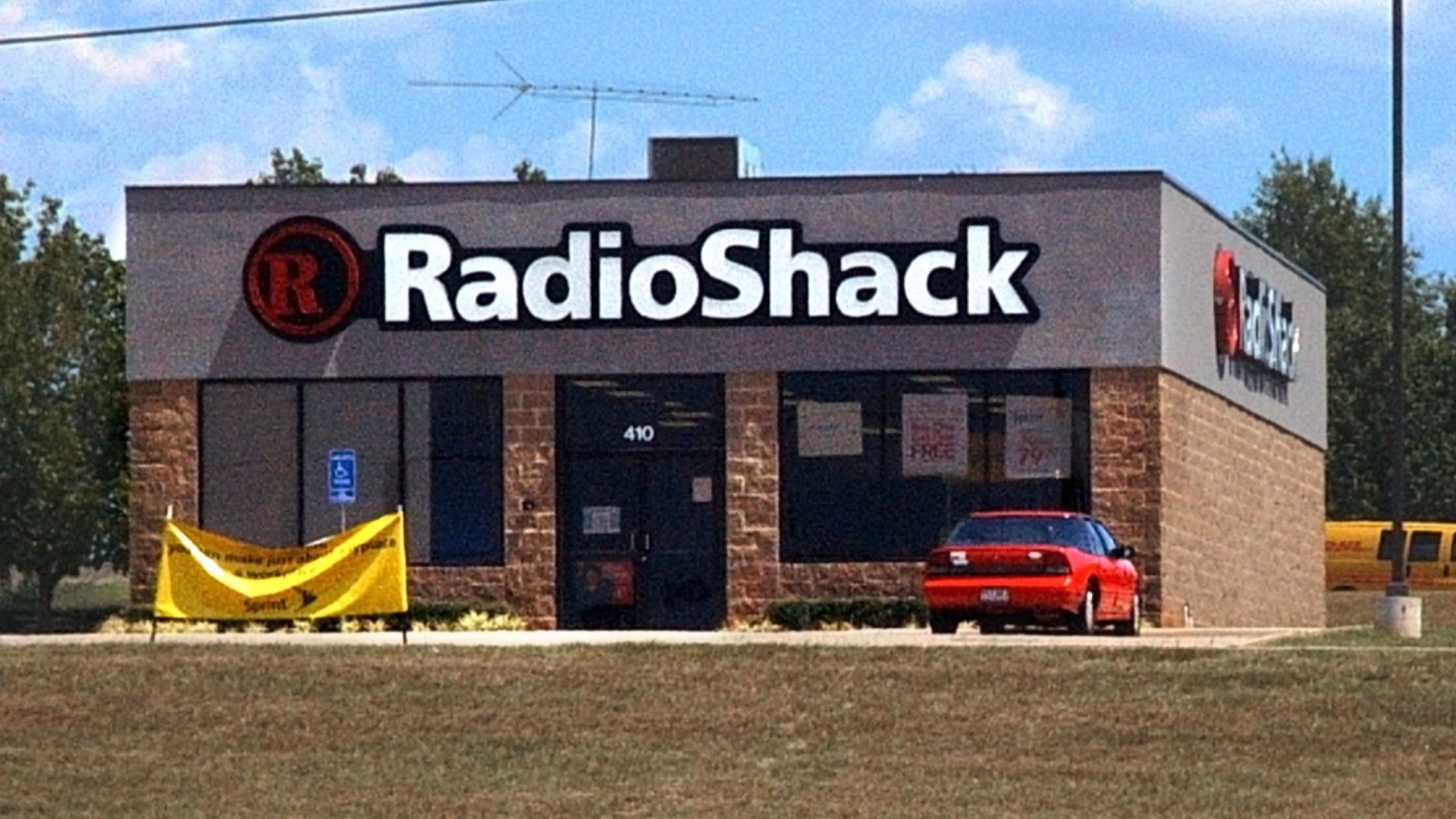 A free-standing RadioShack electronics store in Texarkana. Incidentally, a DHL delivery van is visible on the road behind the store.