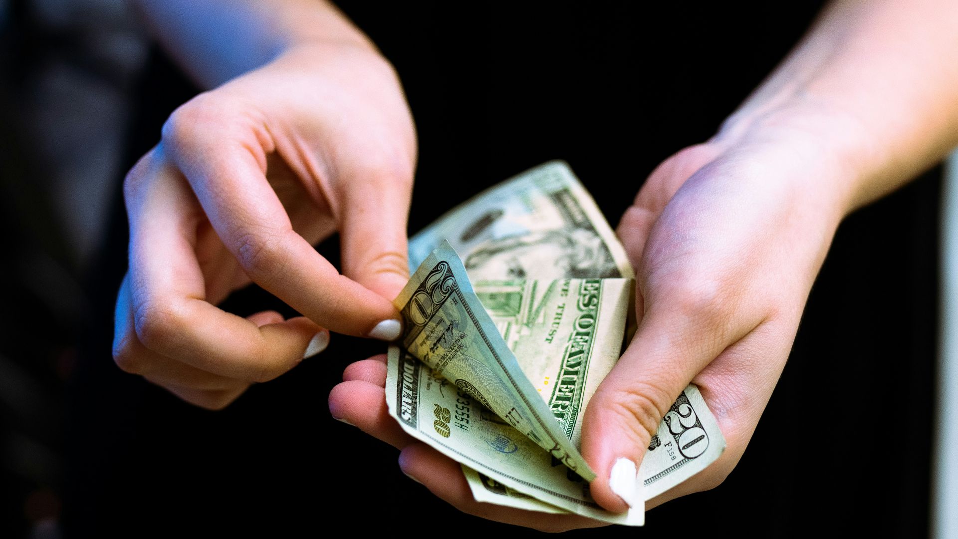 person holding fan of 100 us dollar bill