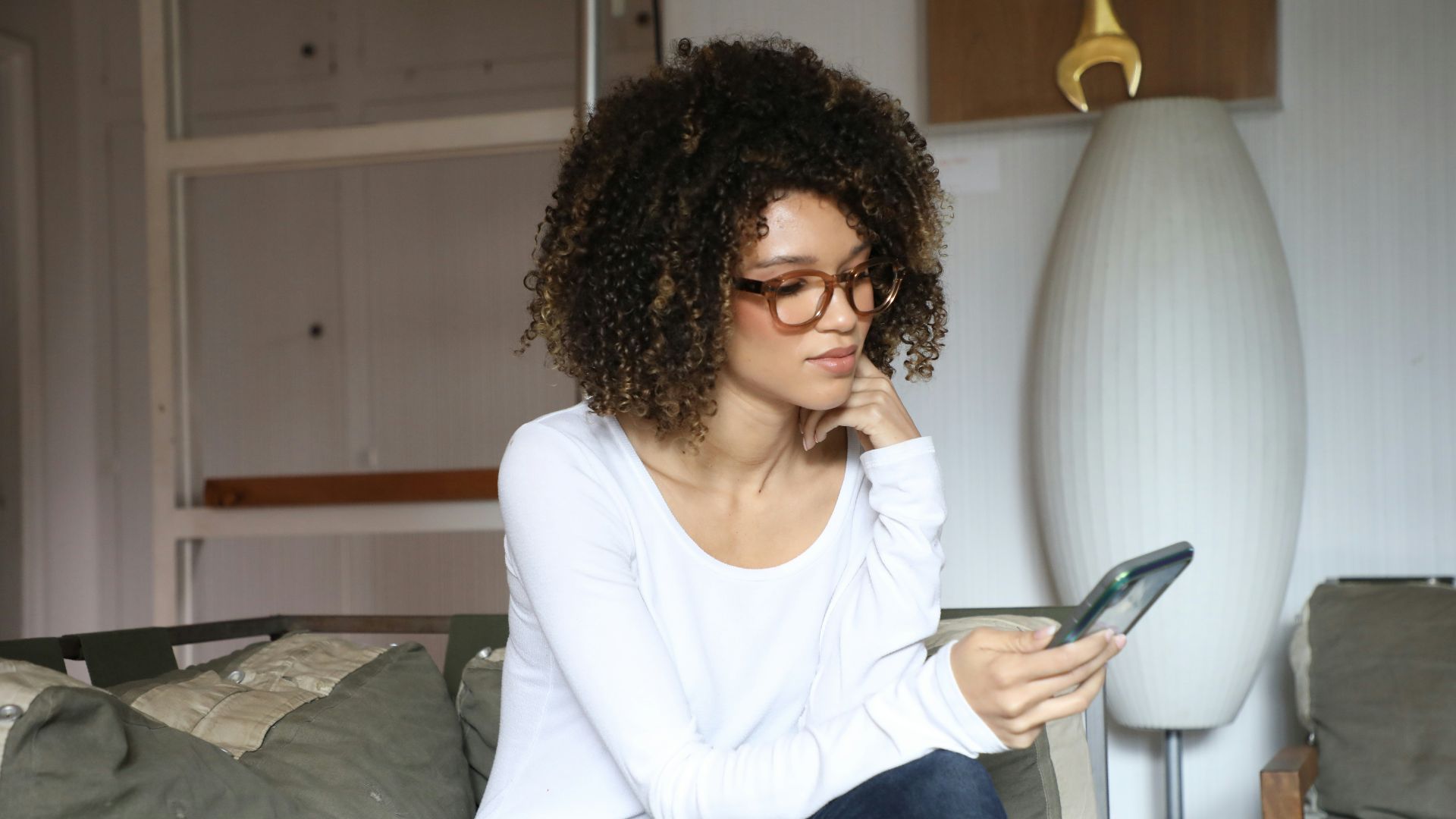 woman in white long sleeve shirt and blue denim jeans sitting on bed