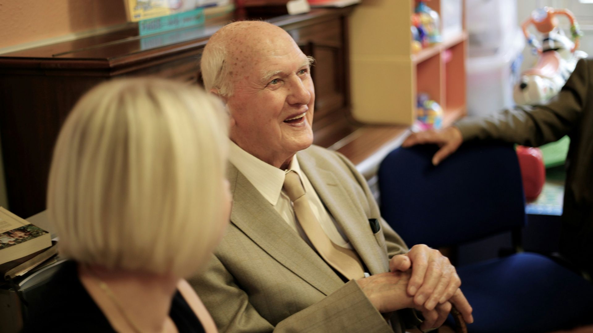 man in brown suit jacket sitting beside woman in black long sleeve shirt