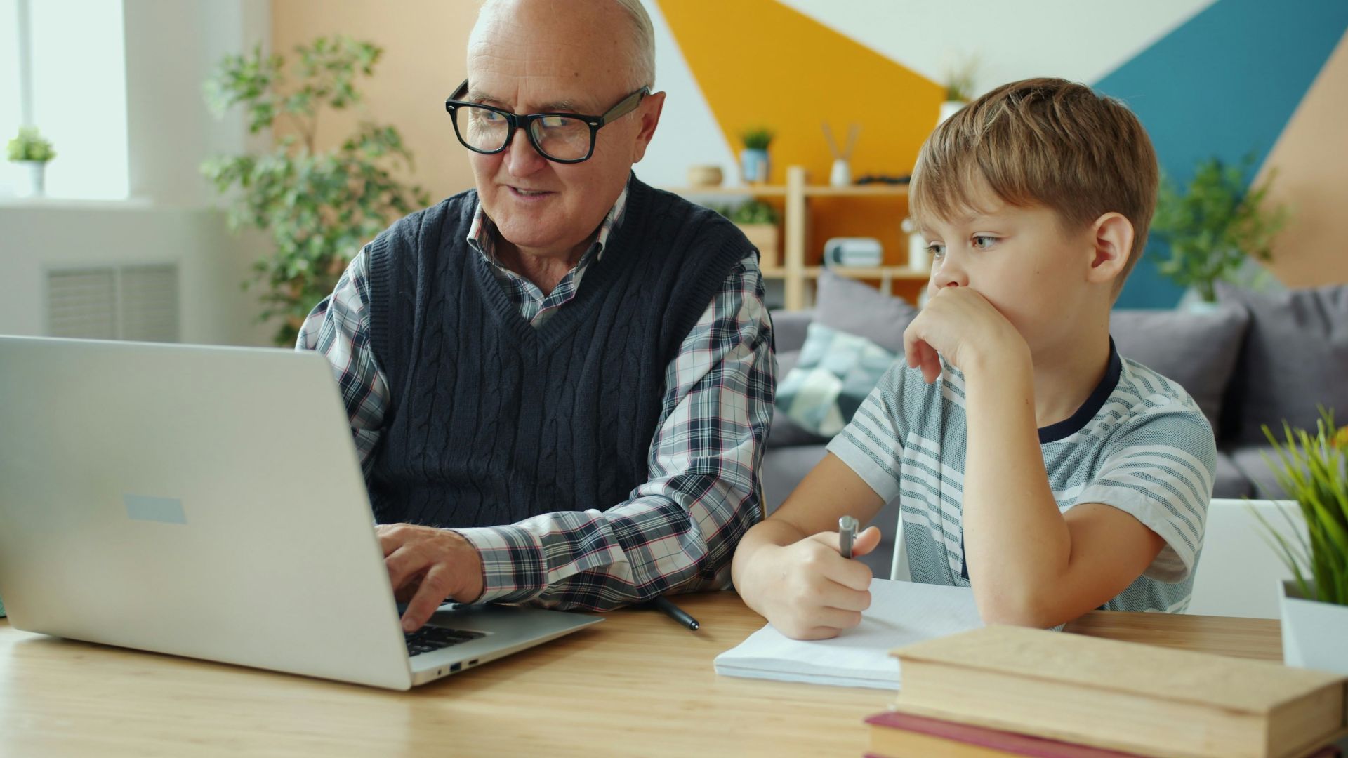 Grandfather and grandson using laptop together at home