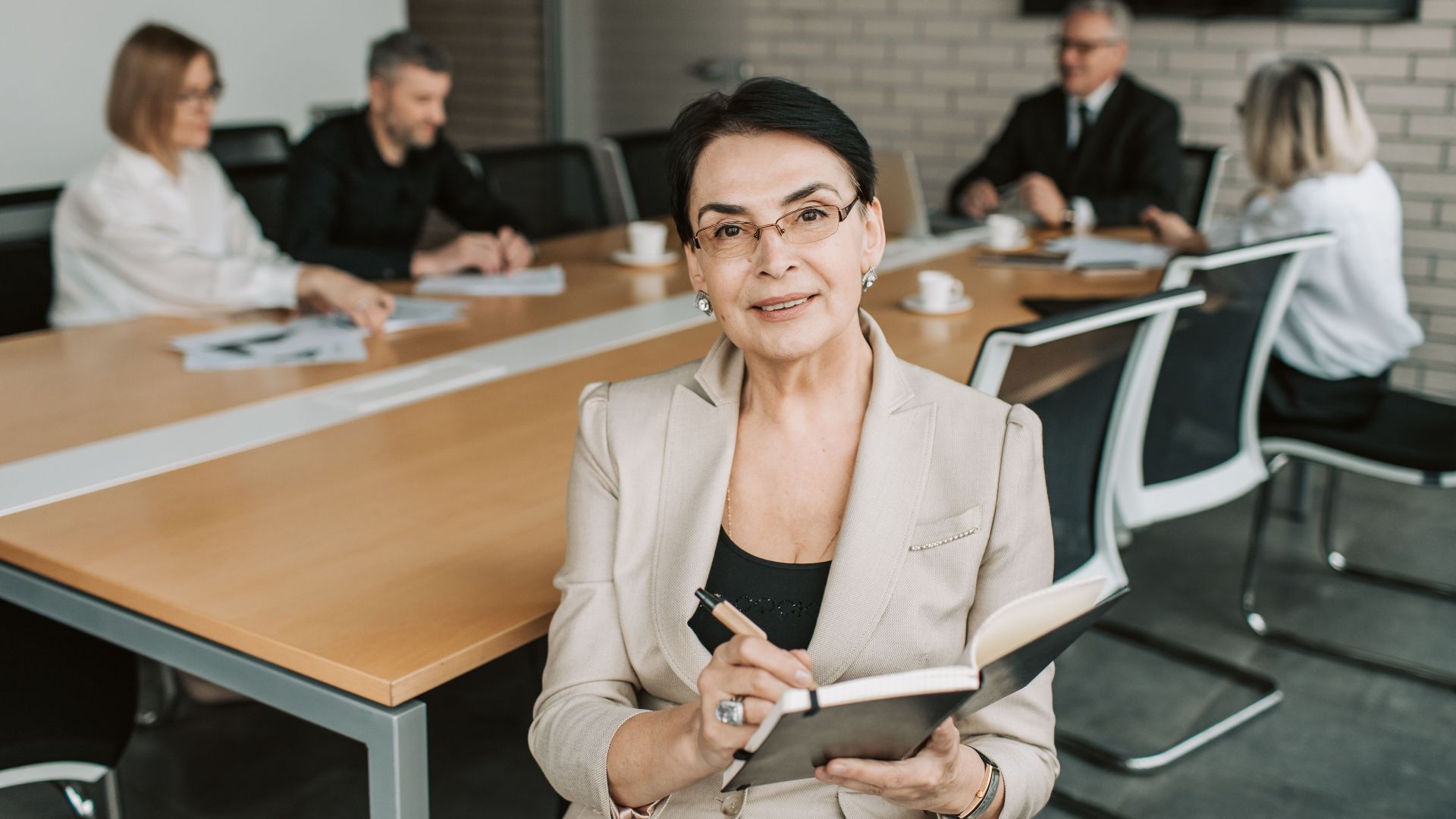 Senior businesswoman leading a meeting with colleagues in a modern office space.