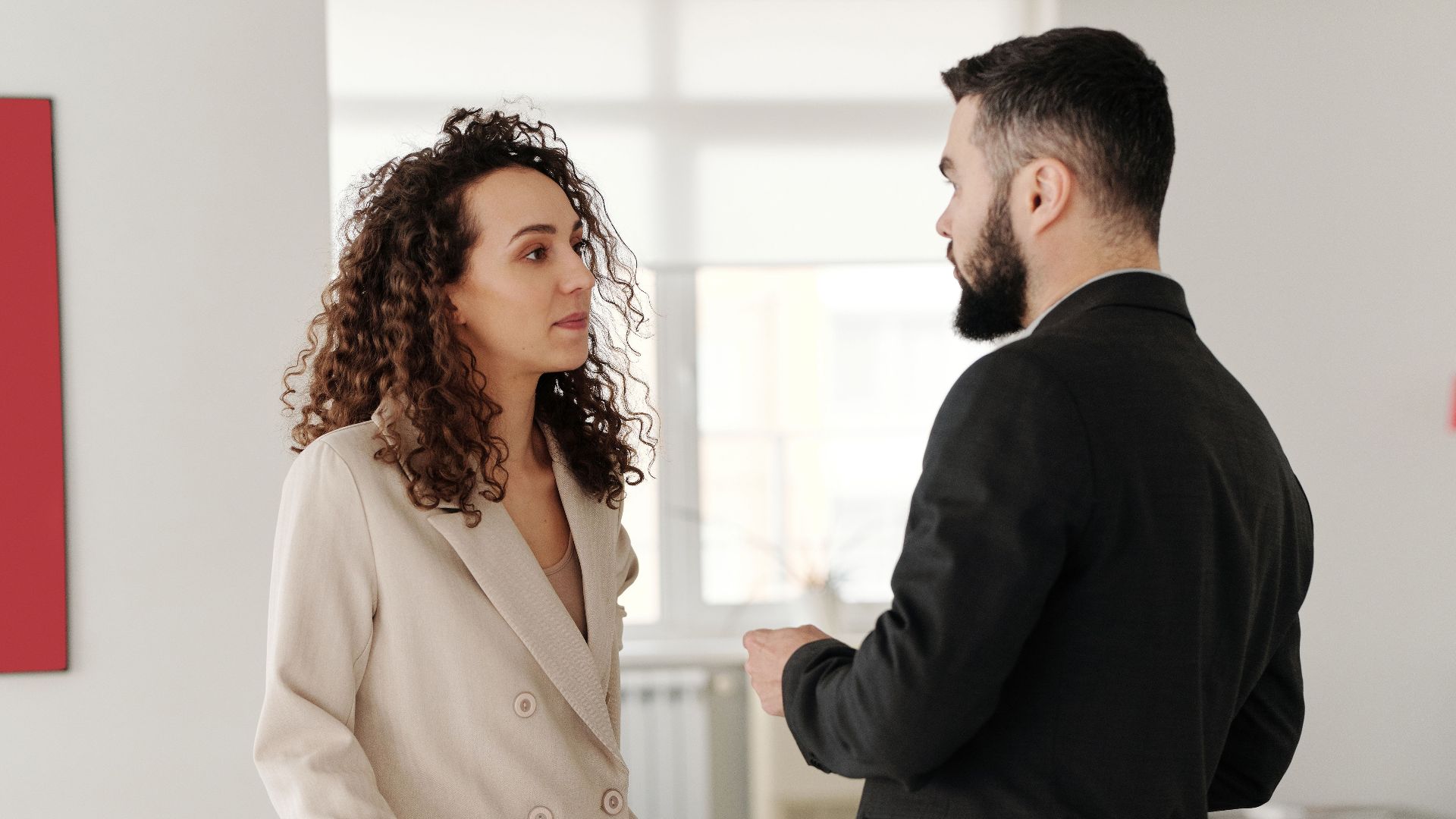 Two professionals engaged in a discussion in a bright, modern office setting.