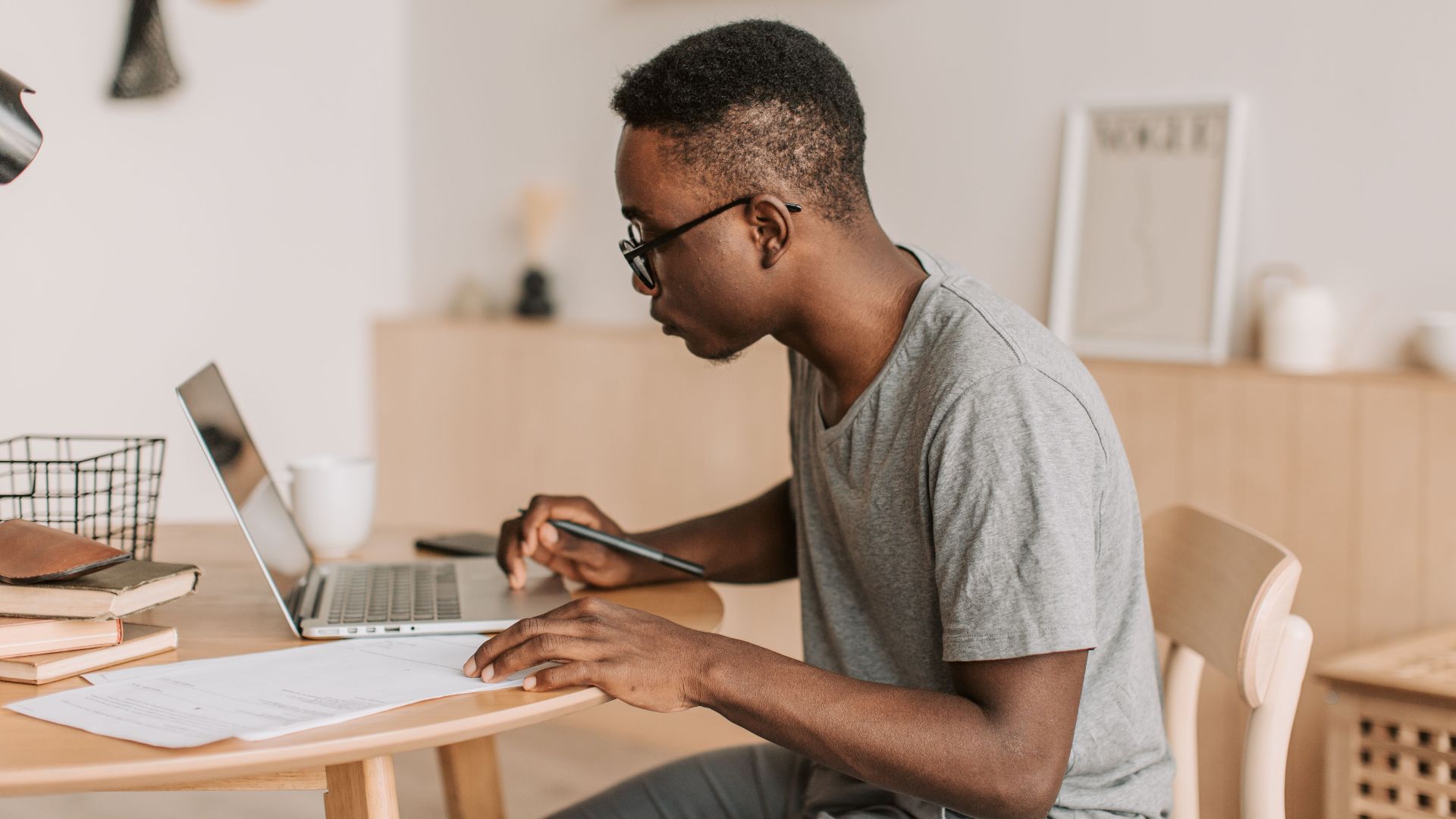 Young man working remotely on a laptop indoors, using digital tools for communication.