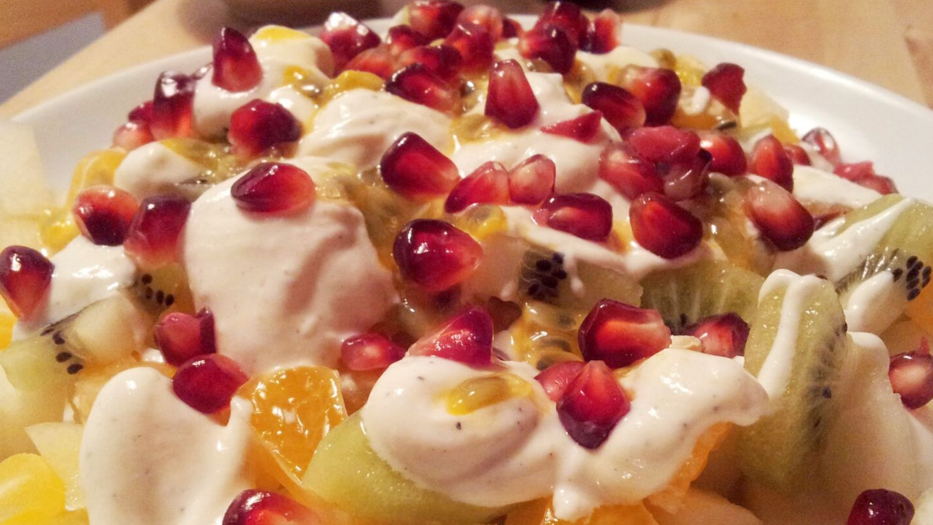 Fruit salad made of pear, satsuma mandarin, kiwifruit, passion fruit, pomegranate seeds, and Greek yogurt mixed with honey, cardamom and vanilla sugar.