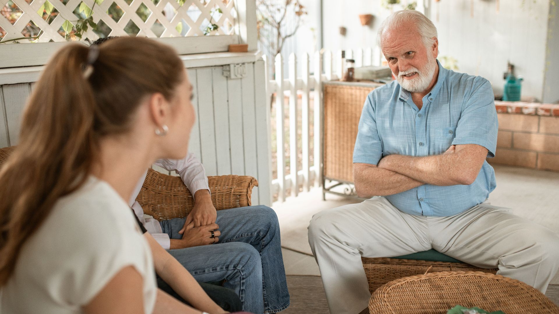Senior man and two adults having a friendly conversation on a spacious veranda.
