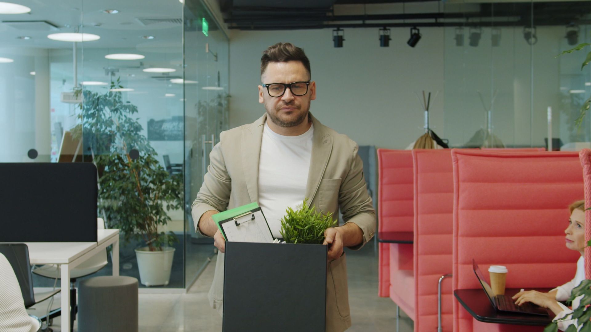 Man carrying a box of belongings, exiting office after job termination.