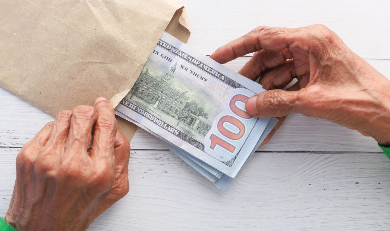 senior women hand putting cash in a envelope.