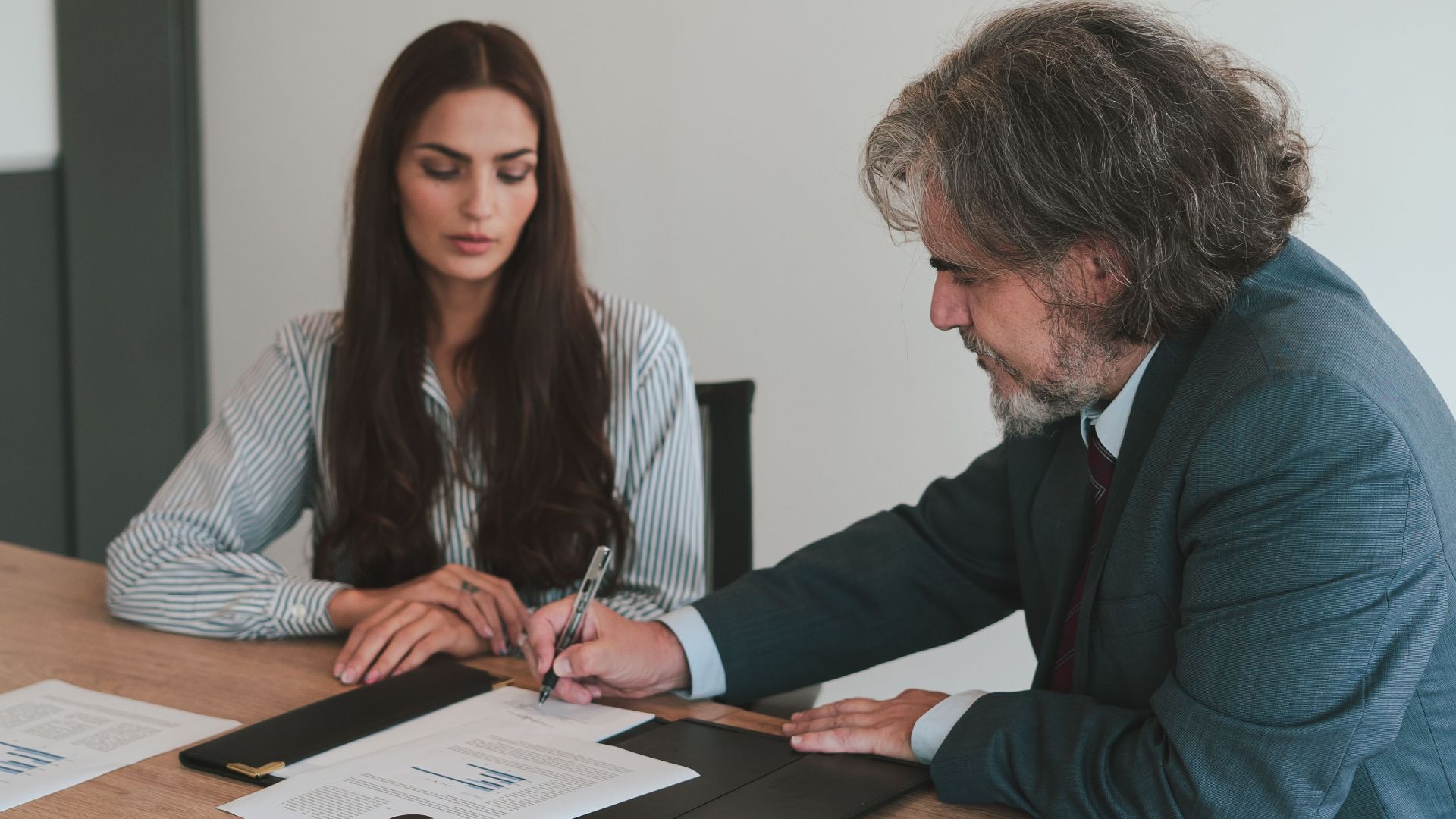 Professional business meeting with two colleagues reviewing documents at an office desk.