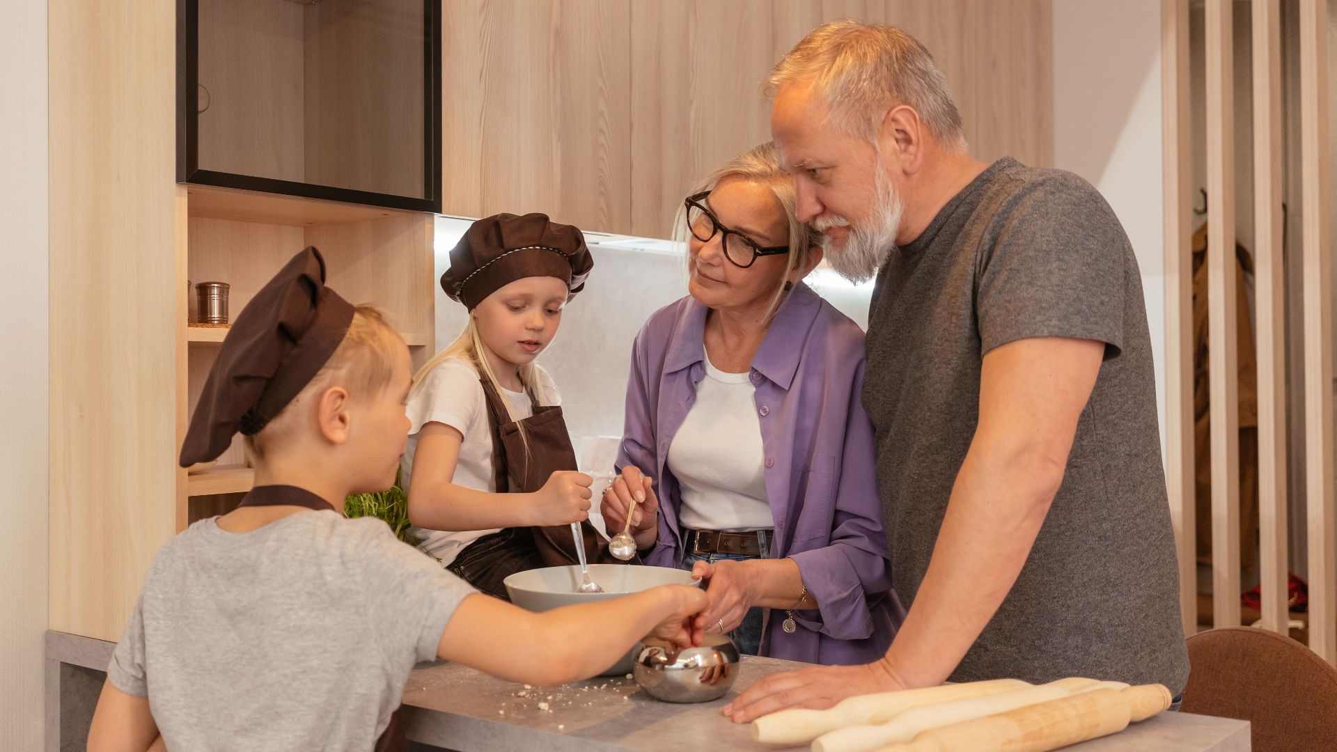 Grandparents and grandchildren cooking together in a cozy kitchen setting.