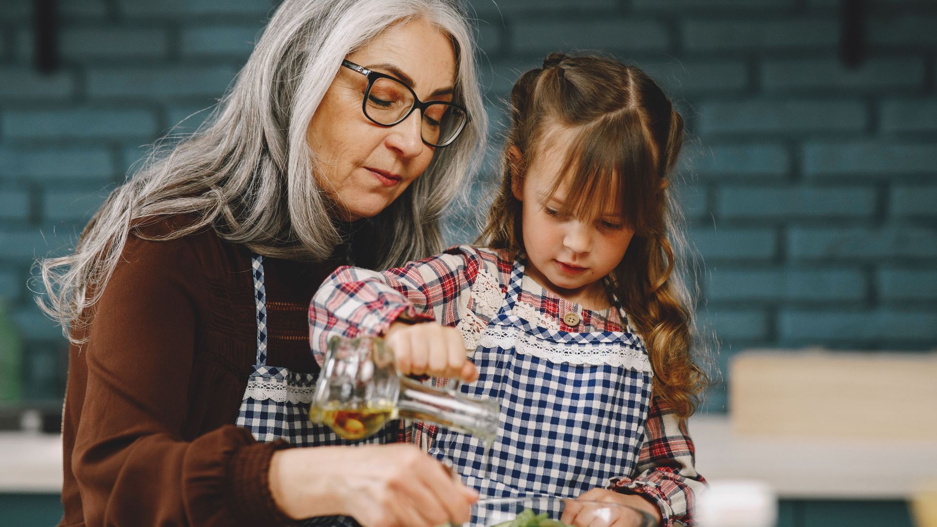A senior woman and young girl prepare a salad in a cozy kitchen setting.